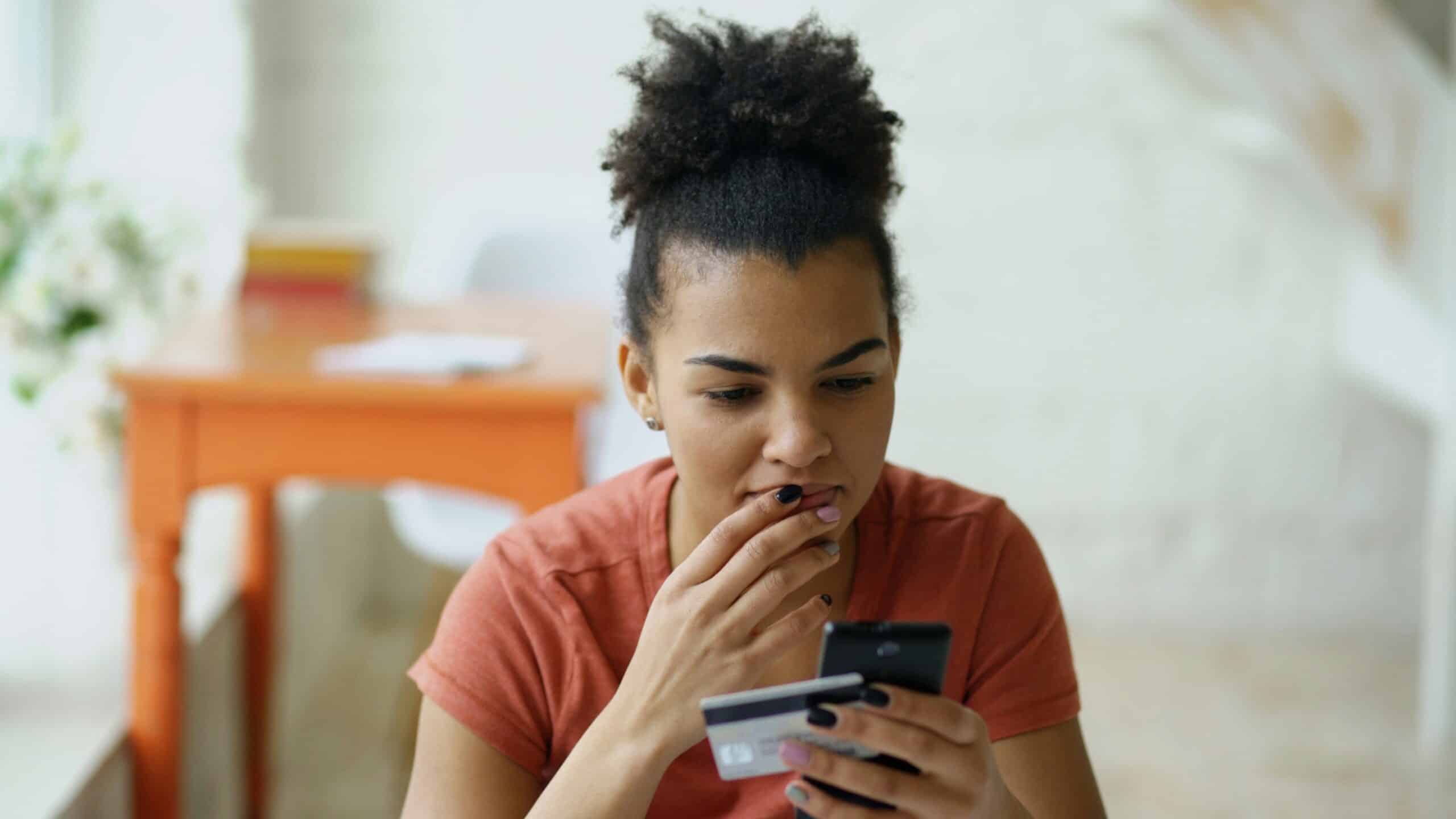 Young woman looking at her phone with a thoughtful expression.